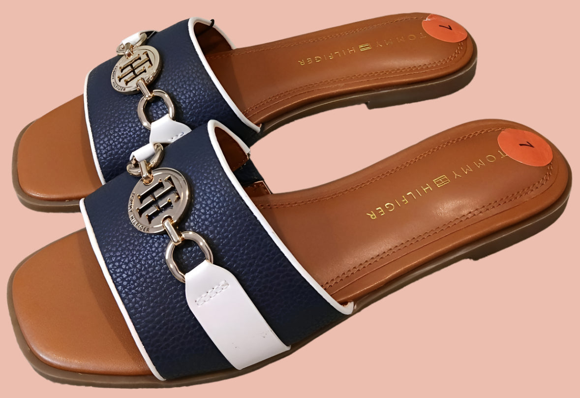 Pair of navy and brown sandals with decorative charm on a light background