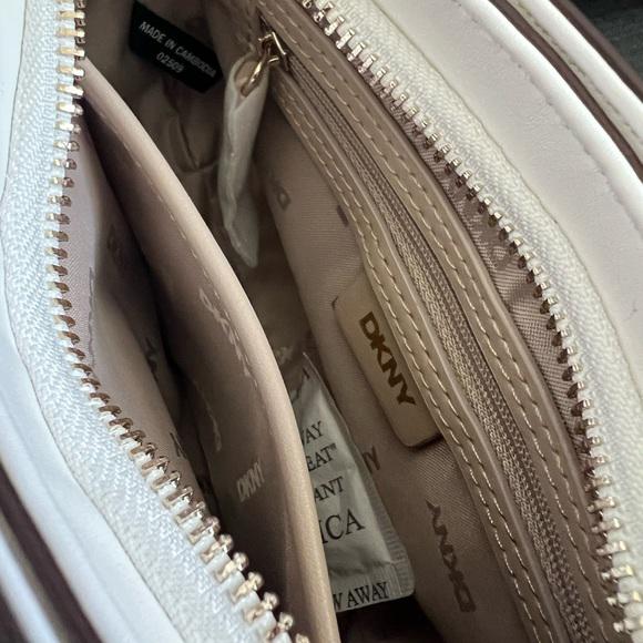 Close-up of a DKNY handbag with a partially open zipper, revealing a branded pouch inside.