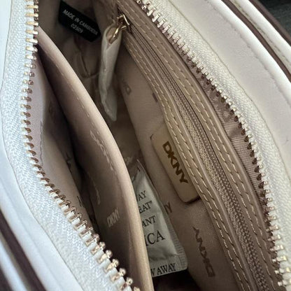 Close-up of a DKNY handbag with a partially open zipper, revealing a branded pouch inside.